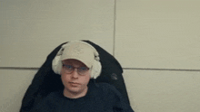 a man wearing a hat and headphones is sitting in a chair .