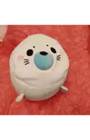 a stuffed seal with a blue nose is laying on a bed