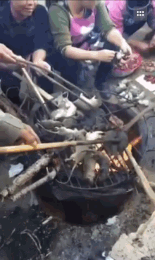 a group of people cooking food on a grill