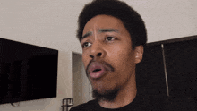 a man with a beard is making a funny face in front of a television