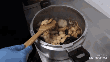 a pot of food is being stirred with a wooden spoon and the words made in animatica are visible