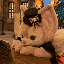 a stuffed animal wearing a top hat with a skull on it is sitting on a table
