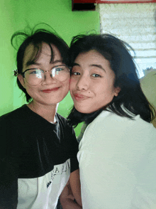 two girls are posing for a picture with one wearing a shirt that says ' aa ' on it