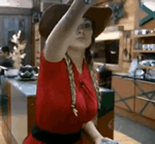 a woman in a red dress and a cowboy hat is sitting in a kitchen .