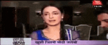 a woman in a blue dress is speaking into a microphone on a tv screen .