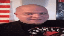 a bald man with a beard is wearing a black shirt with the word hash on it .
