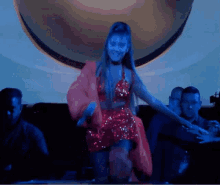 a woman in a red dress is dancing on a stage in front of a globe .
