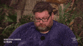 a man wearing glasses and a blue shirt is sitting in front of a palm tree and says in diretta dall honduras