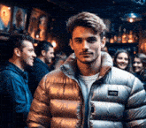 a man wearing a patagonia jacket stands in a crowded bar