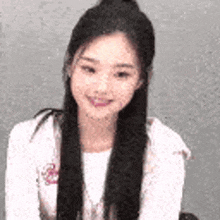 a woman with long black hair is smiling and wearing a white shirt and a white hoodie .