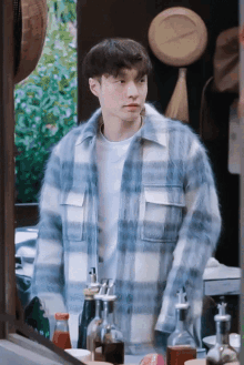 a man in a plaid shirt is standing in front of a table