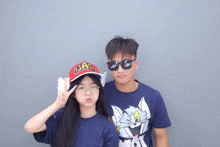 a boy wearing sunglasses and a girl wearing an arale hat pose for a photo