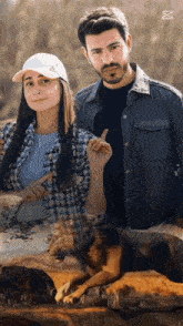 a man and a woman are standing next to each other with a dog behind them