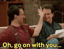 two men are sitting on a couch giving each other a high five while holding a piece of paper .