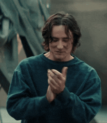 a man in a blue shirt is clapping his hands together