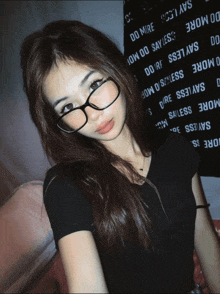 a girl wearing glasses stands in front of a sign that says do more