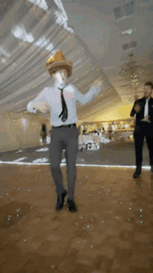 a man wearing a cowboy hat and tie is dancing on a dance floor at a wedding reception .