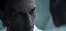 a close up of a woman 's face in a dark room with a man behind her .