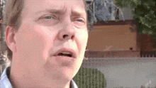 a man is making a funny face in front of a fence .