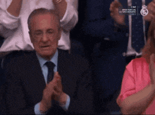 a man in a suit and tie is clapping in a crowd of people