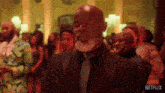 a man in a suit and tie is standing in front of a crowd with netflix written on the bottom