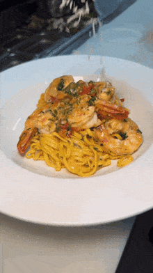 a white plate topped with noodles and shrimp on a table