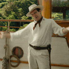 a man wearing a hat and a scarf is standing on a boat