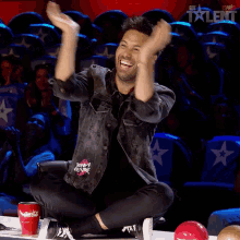 a man is kneeling down with his hands in the air in front of a sign that says got talent on it