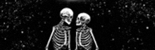 a couple of skeletons are standing next to each other in the dark .