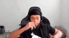 a man wearing headphones and a headband is sitting in a chair and eating something .