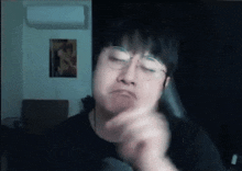a man wearing glasses is making a funny face while looking at the camera in a dark room .