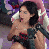 a woman is sitting in a pink chair with a microphone in front of her and a watermark that says xg on the bottom