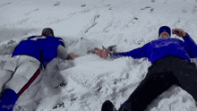 two men are laying in the snow with their arms outstretched ..