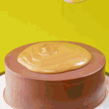 a knife is being used to spread a yellow sauce on a chocolate cake