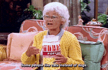 an elderly woman wearing a yellow sweater and an apron that says popcorn on it