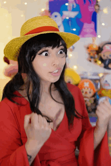 a woman wearing a straw hat and a red dress making a funny face