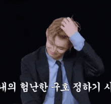 a man in a suit and tie holds his hand to his head