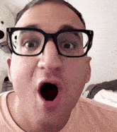 a man wearing glasses makes a surprised face with his mouth open