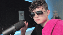 a young man wearing sunglasses and a pink towel is standing in front of a microphone