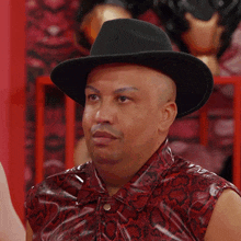 a man wearing a black hat and a red shirt with a snake print