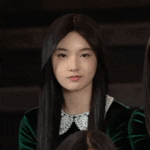a girl with long black hair and a white collar holds her hand to her face