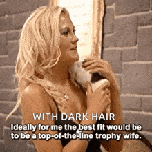 a blonde woman with dark hair is standing in front of a mirror .
