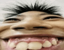 a close up of a person making a funny face with their mouth open and teeth showing .