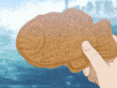 a person is holding a fish shaped biscuit in their hand .