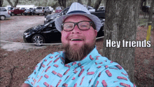 a man with a beard wearing a blue shirt that says hey friends
