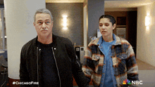 a man and a woman are standing next to each other in a hallway with nbc written on the bottom