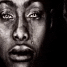 a black and white photo of a man 's face with a tear running down his eye .
