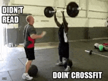 a man is lifting a barbell over his head while another man looks on .