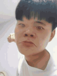 a close up of a man 's face with a white shirt on