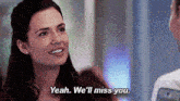 a woman is smiling while talking to a man and saying yeah we 'll miss you .